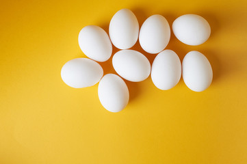 Eggs on a yellow background. Smooth beautiful eggs, space for text. Minimalism. The view from the top.