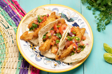 Mexican breaded fish tacos also called ensenada on turquoise background
