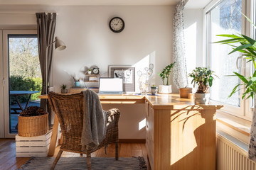 Interior of home office with wooden office desk with laptop near big window. Light, bright and stylish room for work at home. Workplace in scandinavian style. Stay home. - obrazy, fototapety, plakaty
