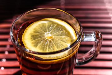 Cup of tea with lemon on wooden background in sunny day in close up for flu prevention. Traditional antiviral drinking. Layout design