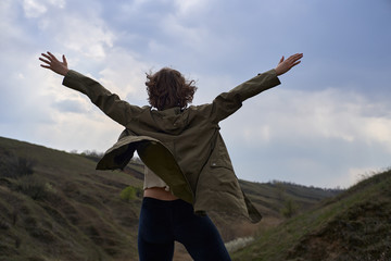 Alone girl on beautiful mountain view feeling free with wind  and sky. Isolated woman on nature background, freedom, post apocalypse