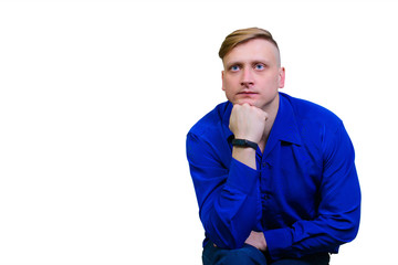 A young man in a blue shirt is thoughtful and looks away.