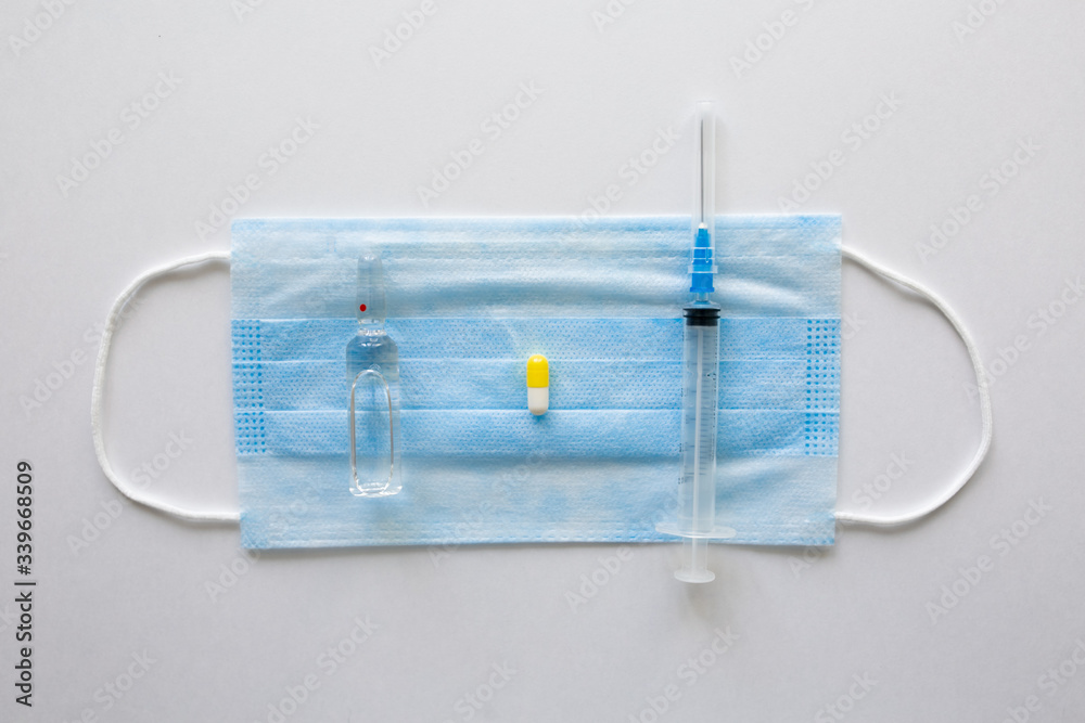 Wall mural coronavirus prevention medicall blue mask, syringe and pills on white background.