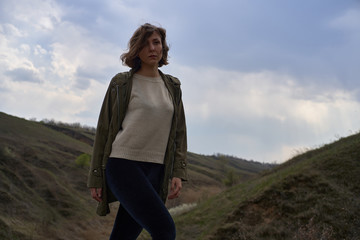 Naklejka premium Alone girl on beautiful mountain view feeling free with wind and sky. Isolated woman on nature background, freedom, post apocalypse