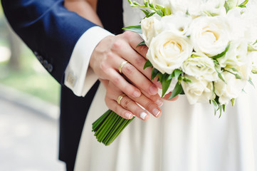 Obraz na płótnie Canvas Cropped close up photo, of chic virile luxurious trendy The and a wedding bouquet. bride and groom holding on hands standing on wedding ceremony . Close-up. Wedding accessories.