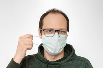 Man takes off surgical mask from his face. End of pandemic coronavirus covid 19 in 2020 year.