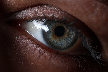 Close up of a sexy woman eye in a moody environment. Looking straight forward.