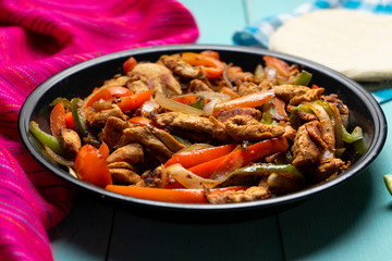 Mexican chicken fajitas on turquoise background