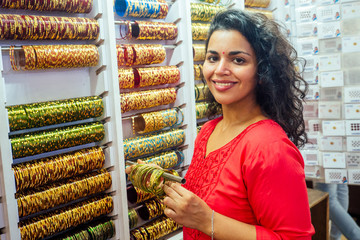 young indian woman show traditional ethnic bracelets in her small market in Goa