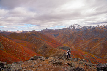 Fototapeta na wymiar The mountains of Tombstone Territorial Park in Northern Canada, Yukon Territory taken in the fall autumn, just as the first snowfall appeared on the mountain tops. Couple hugging on mountain peak. 