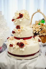 Delicious sweet wedding loaf, decorated with white and red flowers from the mastic. Wedding Bread. Vertical photo