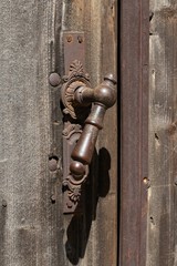 Large metal handle on an old wooden door, design of hardware and