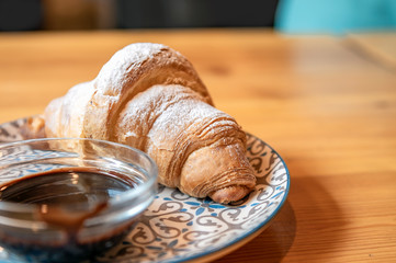 Plate with tasty freshly baked croissant on table. Delicious breakfast with fresh croissants