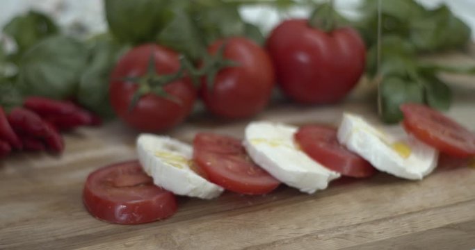 Versare olio extra vergine di oliva su una caprese di pomodoro e mozzarella di bufala italiana