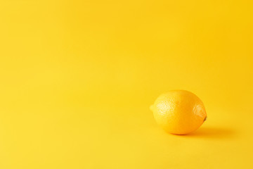 Ripe lemon on yellow paper, minimalism, monochrome.