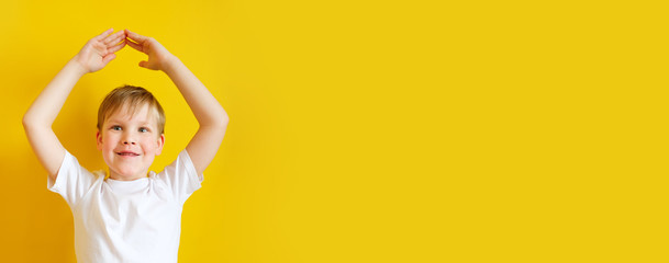 Beautiful happy schoolboy holding hands over his head, as if the roof over the house.