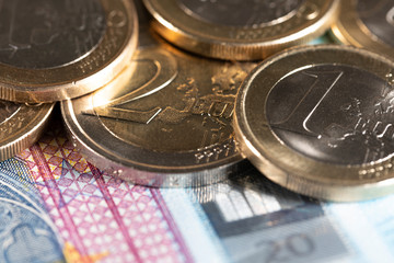 Two euro and one Euro coin closeup on top of a 20 euro bill. European money currency