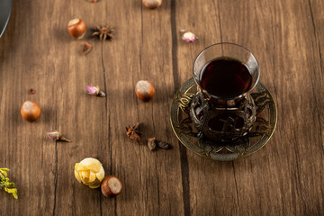 A glass of tea with nuts around on a wooden table