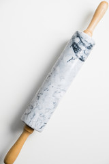 Rolling pin for dough made of gray marble with wooden handles and cradle. On a white isolated background.