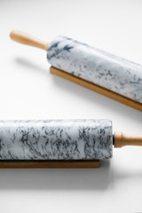 Rolling pin for dough made of gray marble with wooden handles and cradle. On a white isolated background.