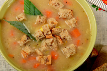 Vegetable soup with sausage and pieces of bread on a flower napkin