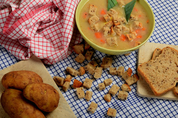 home-made soup made of vegetables in a green bowl with pieces of dry bread