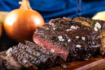 Sliced meat barbecue on a wooden board served with onion
