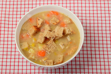 home-made soup made of vegetables in a green bowl with pieces of dry bread