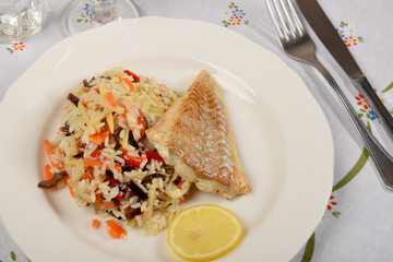colorful rice with vegetables and fried fish on a white plate