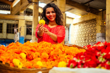 portrait of brunette indian florist female in floral bazar looking at camera and smile