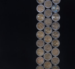 Euro coins on a black background lie in a line. Copy space