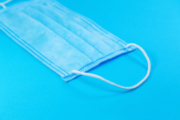 disposable face mask on blue background, respiratory protection