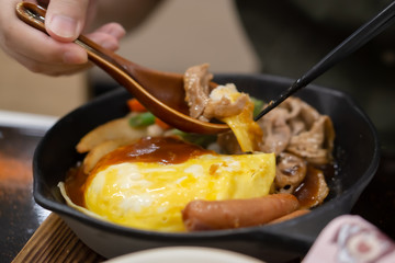 A man-eating Egg Lava Donburi Japanese food style omelet and fried pork with soy sauce in a rice bowl.