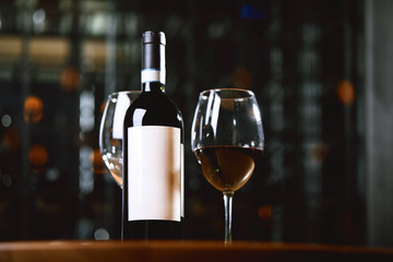 A bottle of wine and glasses on the table, against the background of a wine shakafa. Serving and serving wine. Winemaking concept, copy space.