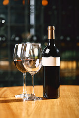A bottle of wine and glasses on the table, against the background of a wine shakafa. Serving and serving wine. Winemaking concept, copy space.