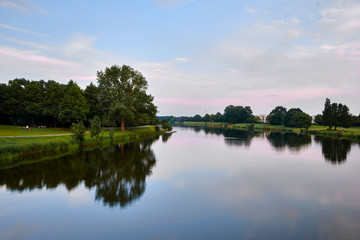 Fototapeta na wymiar Water reflections of a serene river scene with a colourful sky in summer