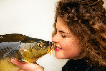 She loves fish- Young beautiful woman with curly and a carp in her hand