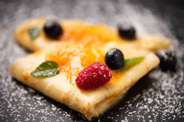 Close up of crepes with powdered sugar and jam