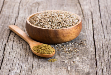 Pile of dry caraway spice with ground caraway powder in wooden spoon. Healthy food cumin spice...
