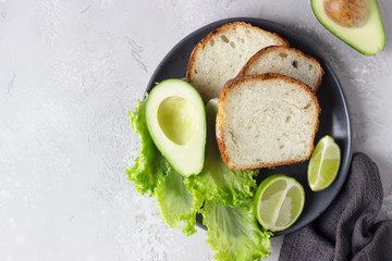 Sliced homemade no knead bread with avocado. The concept of homemade bakery without yeast. Light grey stone background. Top view.