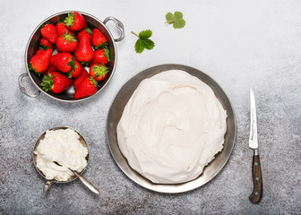 Homemade baked meringue shell with whipped cream and fresh strawberries. Step by step recipe of Pavlova cake. Top view. Copy space.