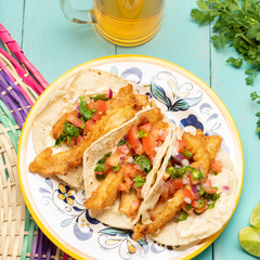 Mexican breaded fish tacos also called ensenada on turquoise background