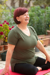 Mature beautiful woman doing yoga in the garden of her house. The woman who is at home in quarantine has a good time at home by doing sports.