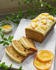 Vegan orange loaf cake and  slices.Homemade citrus cake with white cashew cream on top. Green...