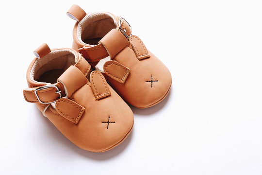 Pair of brown leather kids shoes on white background.