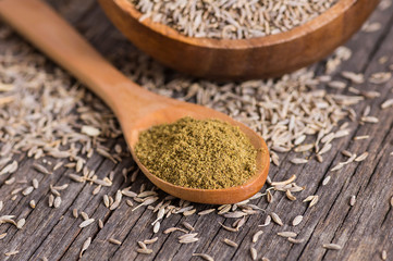 Pile of dry caraway spice with ground caraway powder in wooden spoon. Healthy food cumin spice concept ( Cuminum cyminum )