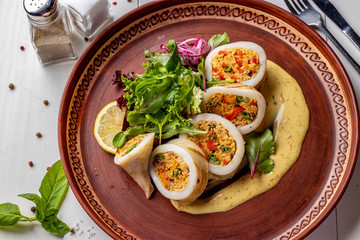 Squid stuffed with couscous and vegetables served with sauce and green salad, Closeup, Restaurant menu, Horizontal format