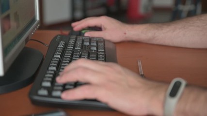 Turin, Piedmont, Italy. April 2020. The hands of a Caucasian man type on the keyboard and use the mouse. Selective focus on the keyboard. Work from home: blurred background of an apartment.