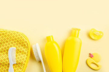 Spa and bath concept. Baby bath set. Rubber duck, washcloth, soap bottle, shampoo, towel and comb on yellow background.