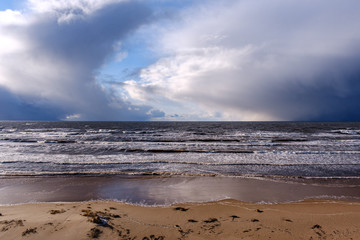 Fototapeta na wymiar The coast of the Baltic Sea with waves and blue skies with white clouds